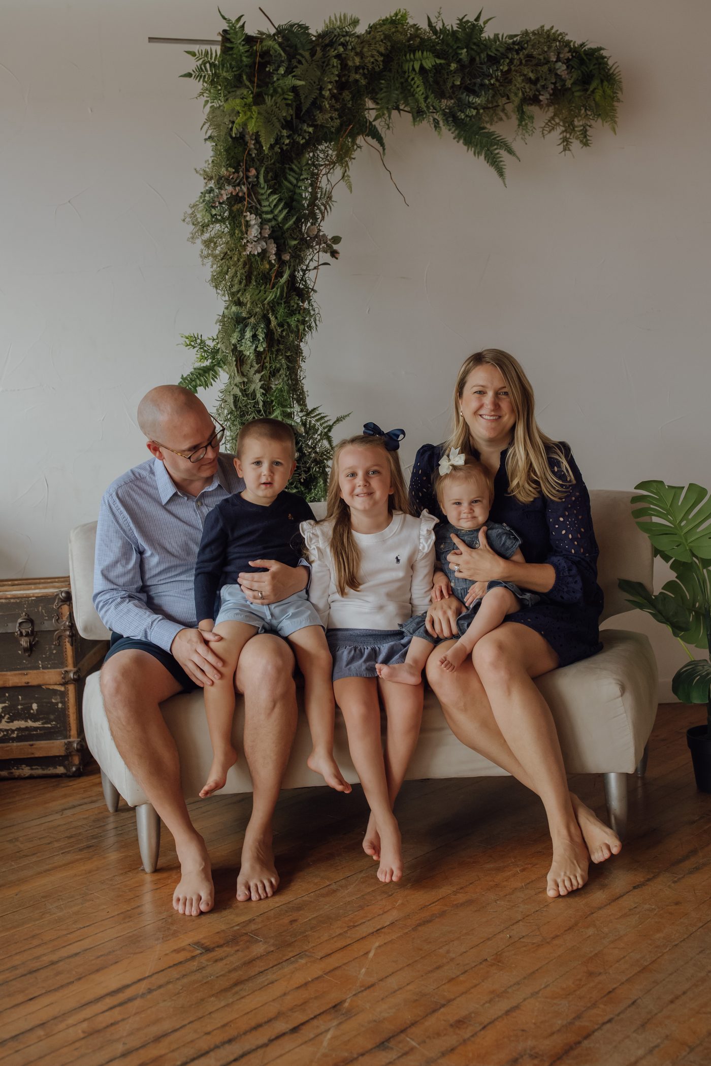 Clayton and Mo on a couch with their three kids under a green garland